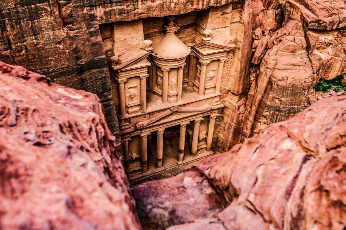 View of Al-Khazneh, Petra's ancient carved rose-red sandstone facade framed between canyon walls in Jordan