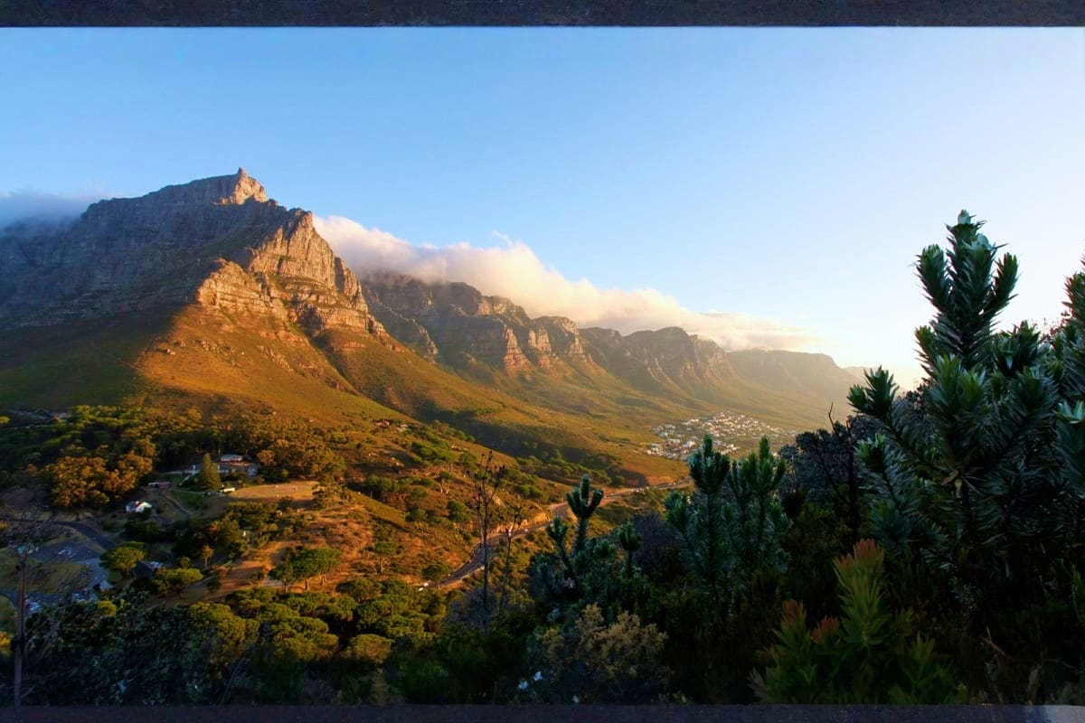 Table Mountain in Cape Town at sunset with golden light illuminating layered rock formations and indigenous vegetation in for