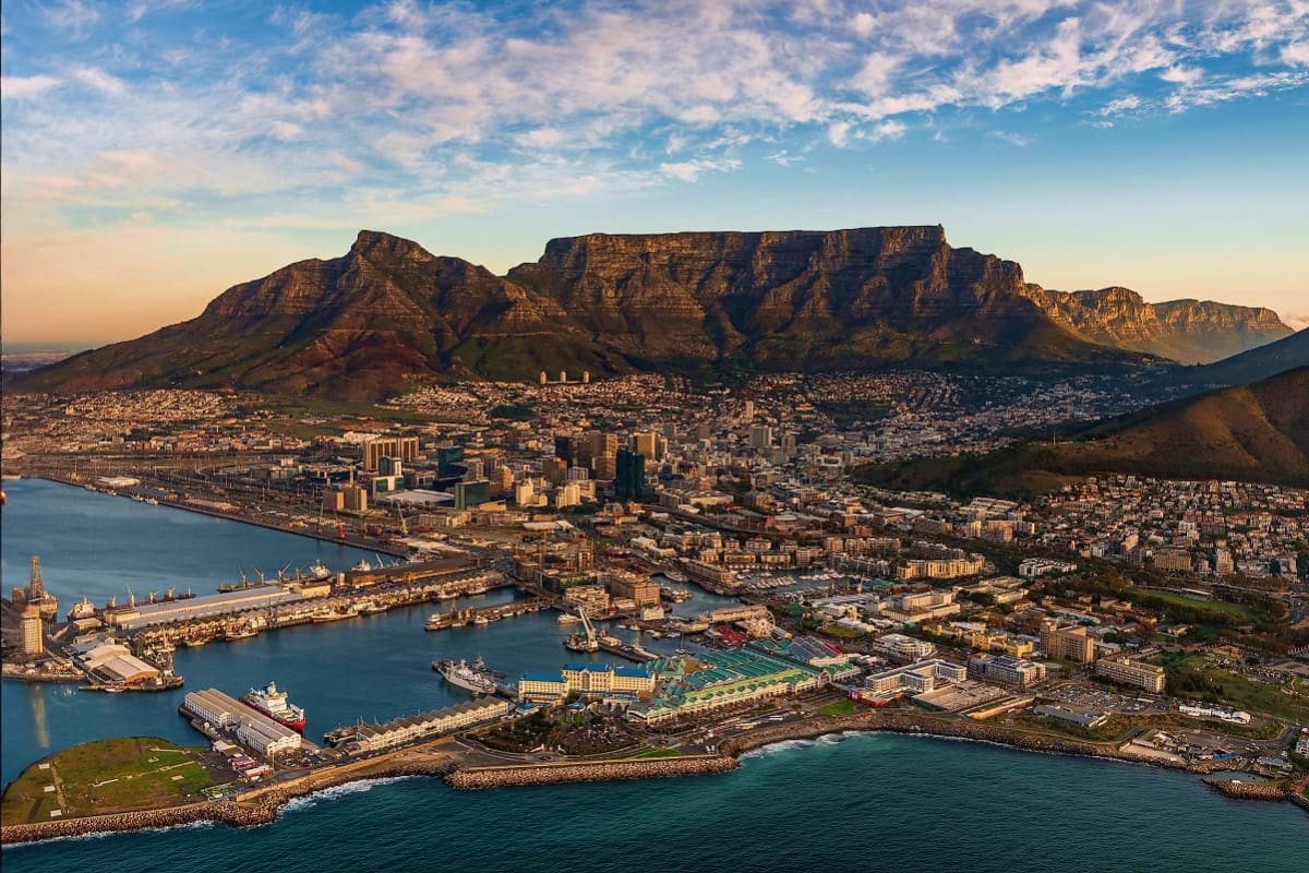 Aerial view of Cape Town with Table Mountain, city skyline, and harbor with ships docked in the blue waters