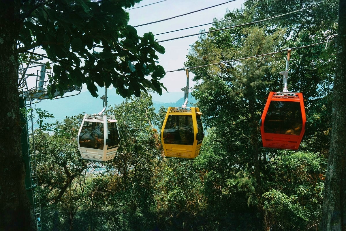 Cable car gondolas suspended over forested mountainside with lake view in New Zealand landscape