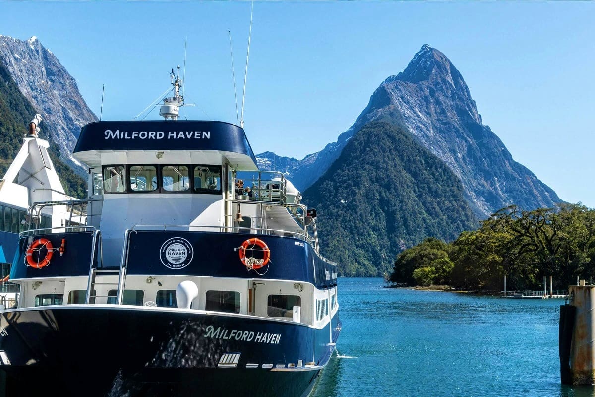 Milford Haven cruise boat docked in Milford Sound with dramatic mountain peaks and turquoise water in New Zealand