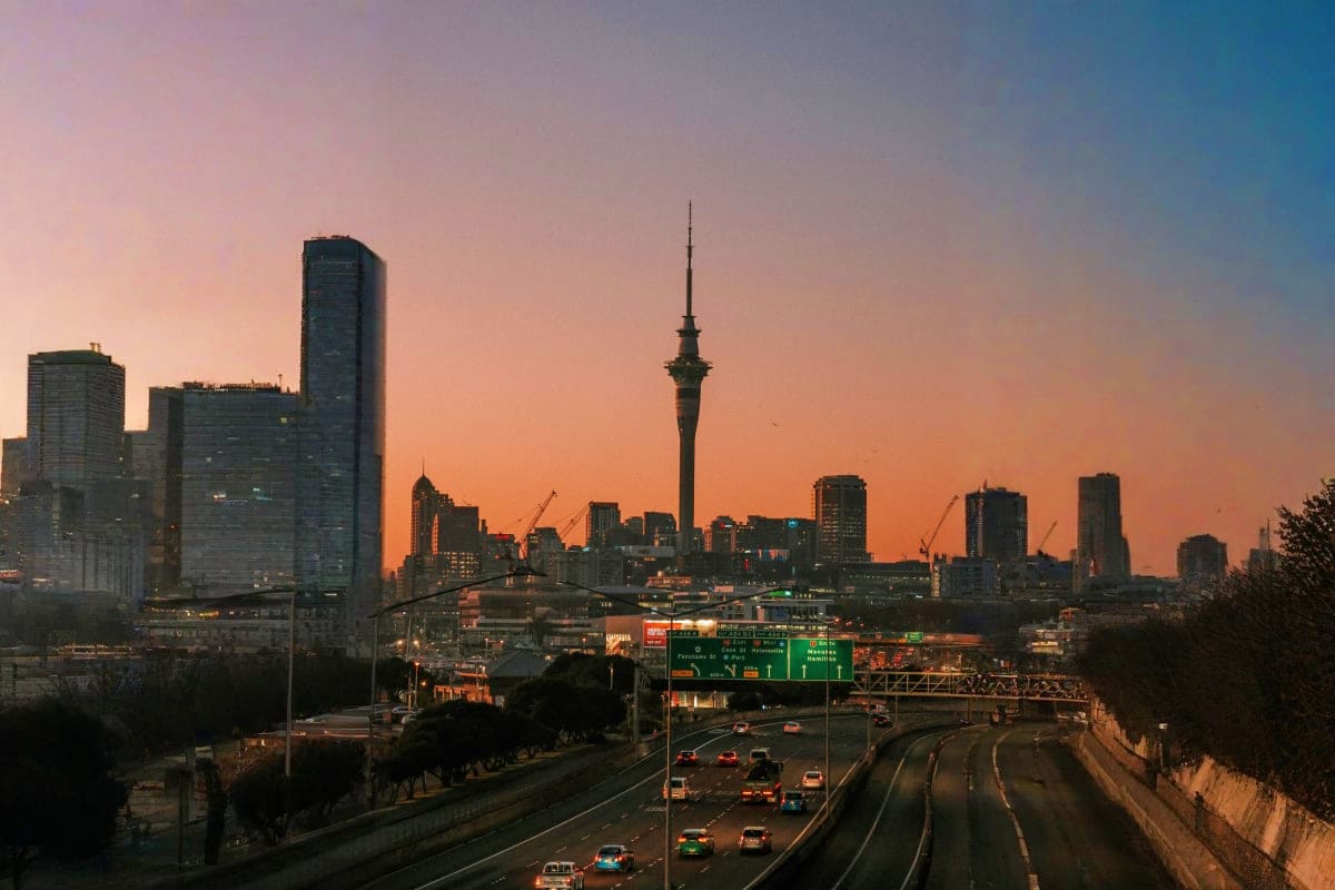 Auckland city skyline at sunset with Sky Tower and highway traffic, New Zealand