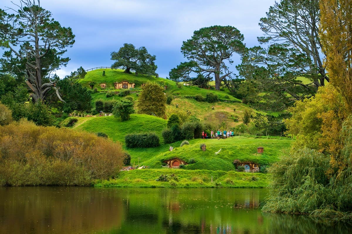 Hobbiton Movie Set in Matamata with rolling green hills, hobbit holes, and visitors exploring the Lord of the Rings filming l