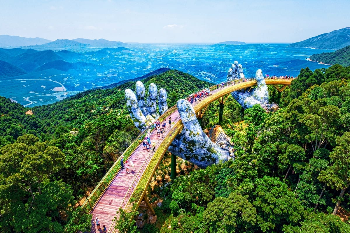 Golden Bridge with giant stone hands in lush mountains overlooking blue ocean valley in Phu Quoc, Vietnam