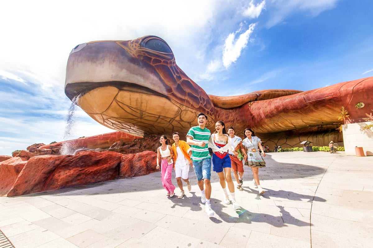 Group of tourists jogging in front of a giant turtle sculpture landmark at Phu Quoc tourist attraction under blue sky