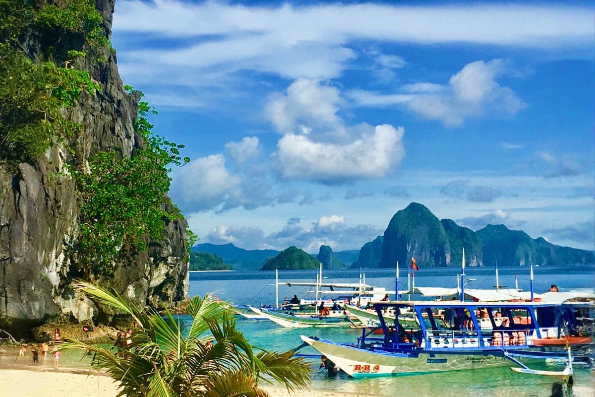 Philippines Island Escape with Manila El Nido and Cebu Tropical beach in El Nido with limestone cliffs, traditional boats, and mountainous islands in clear turquoise waters under b