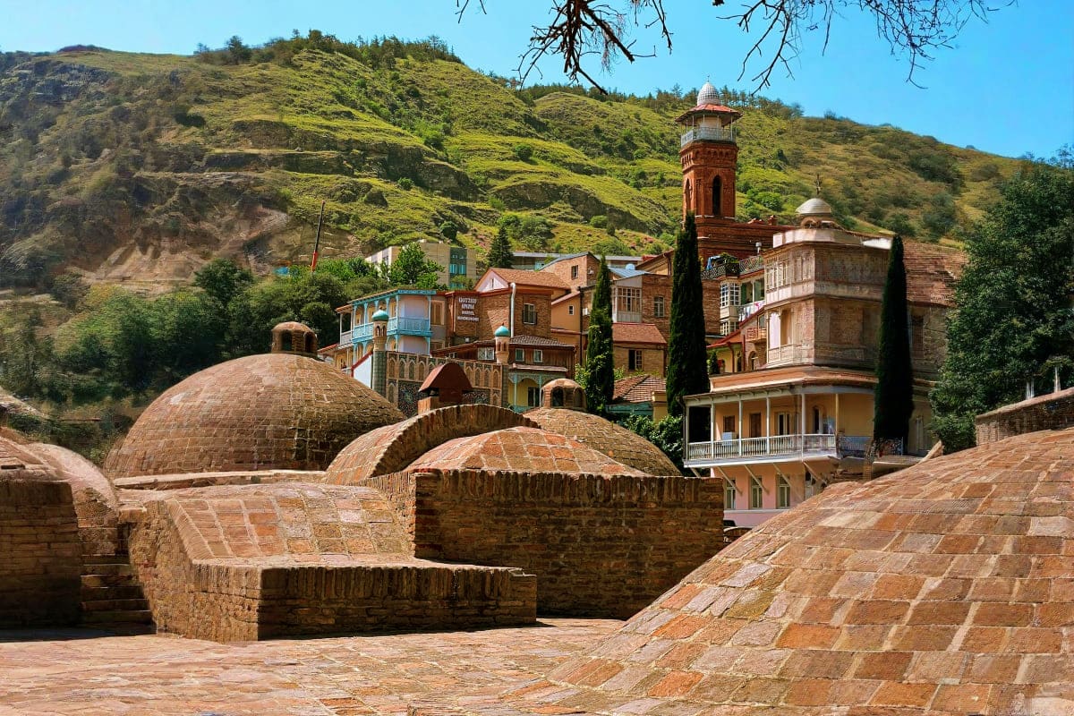Historic Abanotubani bathhouse complex with traditional domed brick structures in Tbilisi, Georgia, with residential building
