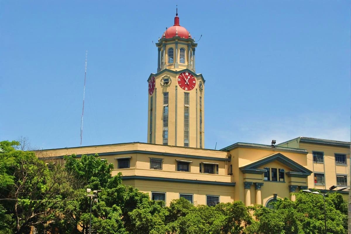 Beyond Manila Historic clock tower with red dome and yellow building facade surrounded by green trees under clear blue sky