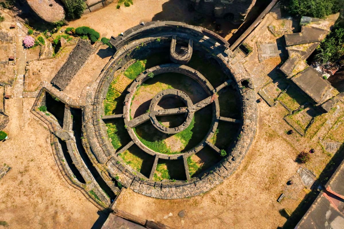 Beyond Manila Aerial view of concentric circular stone fortress with water-filled moat and moss-covered walls surrounded by sandy grounds a