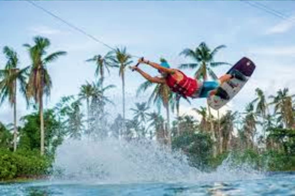 Simply Siargao Kite surfer in action on tropical beach with palm trees and clear water in Siargao