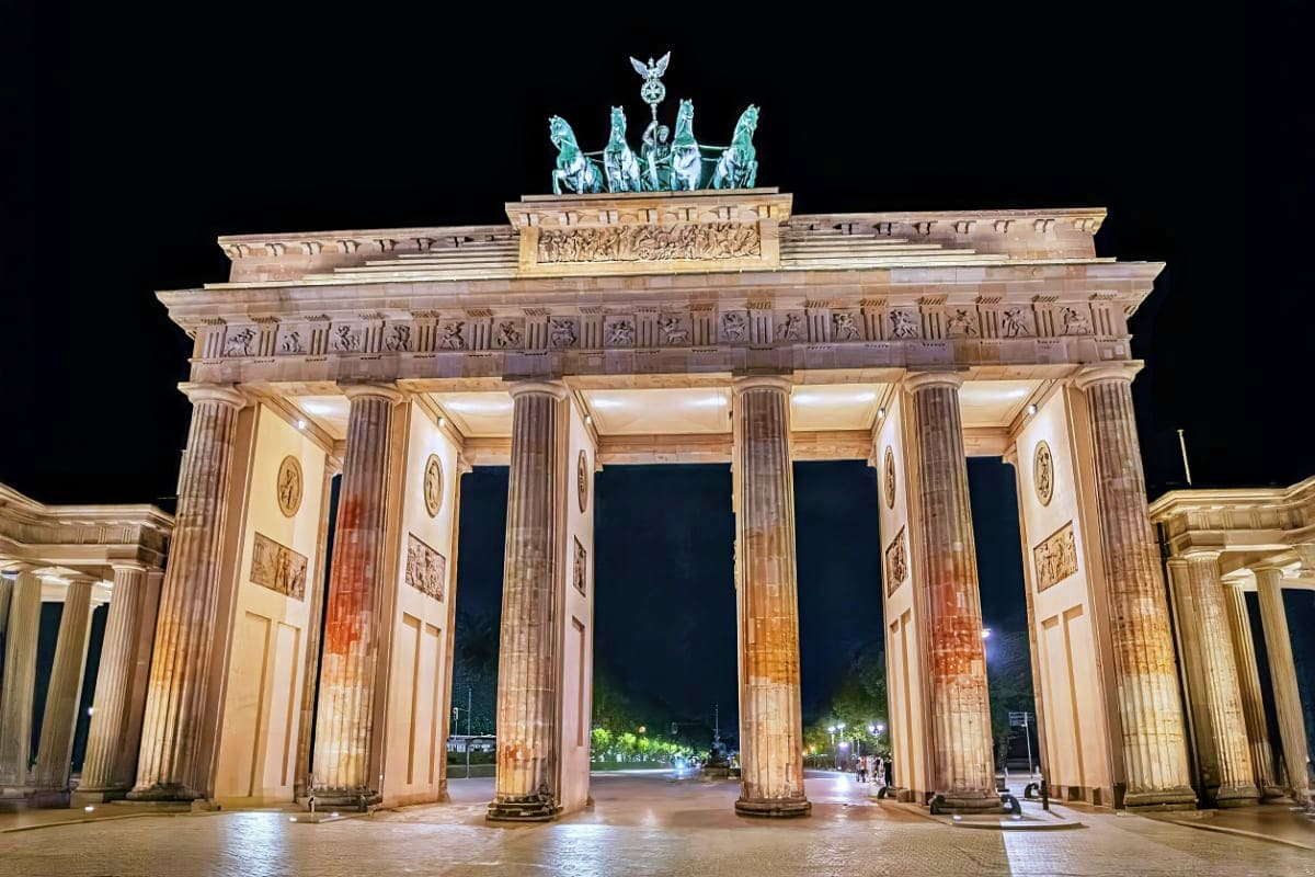 Brandenburg Gate illuminated at night in Berlin, Germany, with classical stone columns and chariot sculpture on top