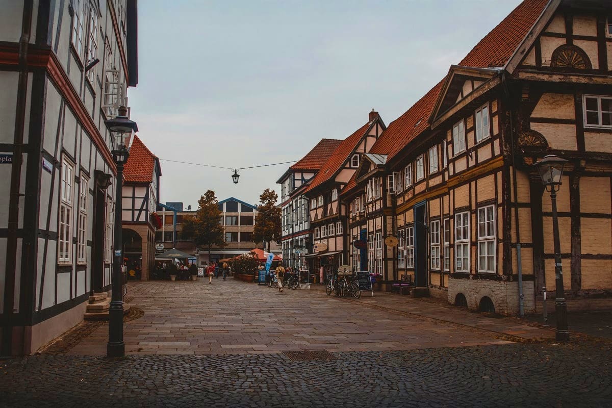 Historic German half-timbered buildings lining a cobblestone street in a medieval town square with pedestrians and bicycles