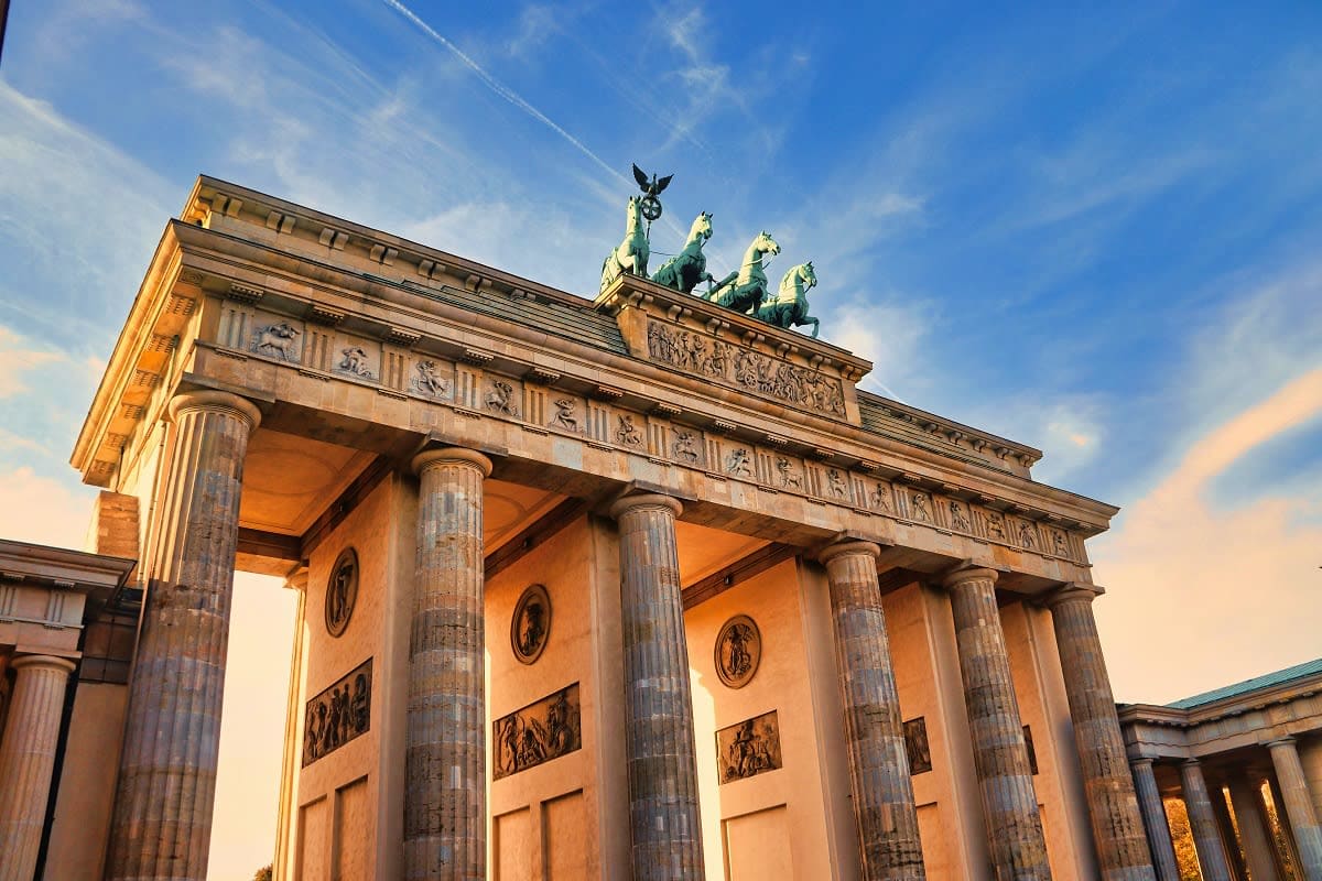 Brandenburg Gate in Berlin with illuminated neoclassical columns and quadriga sculpture on top against blue sky
