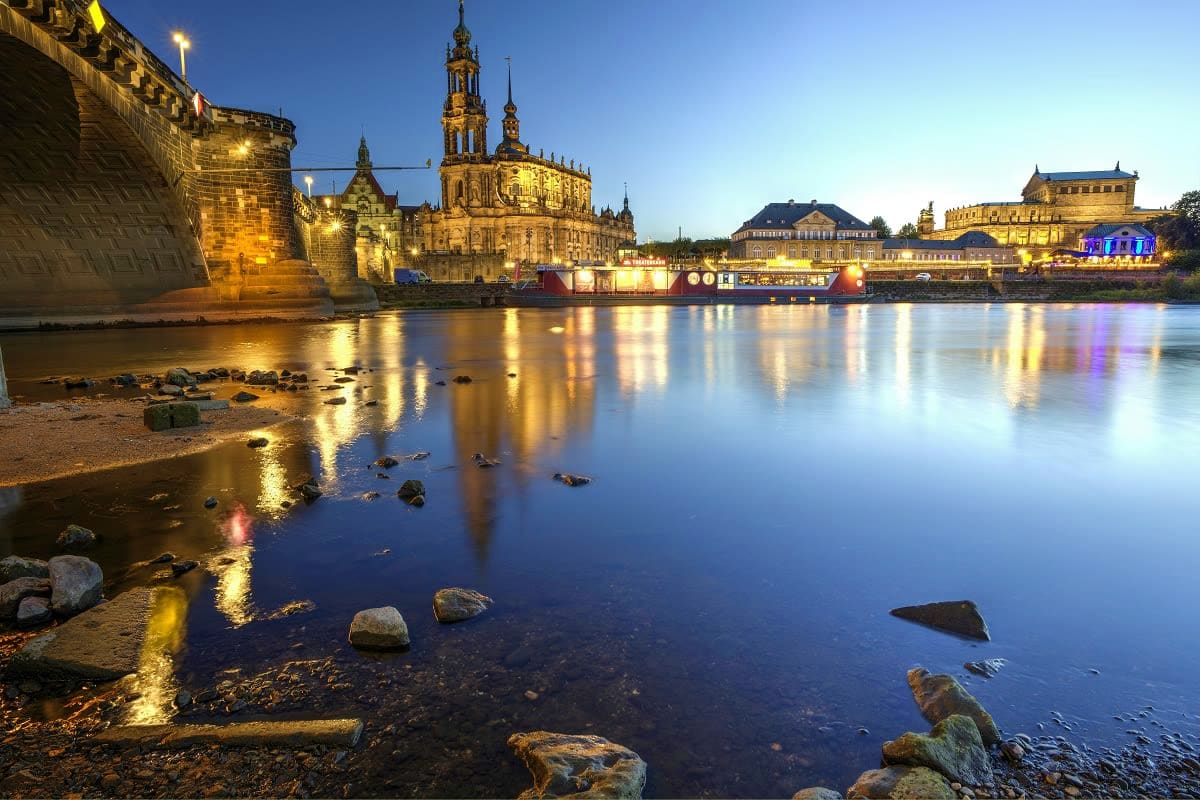 Dresden skyline at dusk with illuminated historic buildings and cathedral reflected in calm Elbe River water