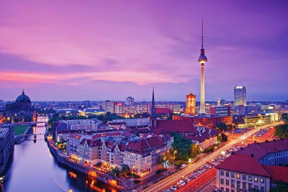 Berlin cityscape at dusk with illuminated TV Tower, Spree River, and historic architecture under purple sky