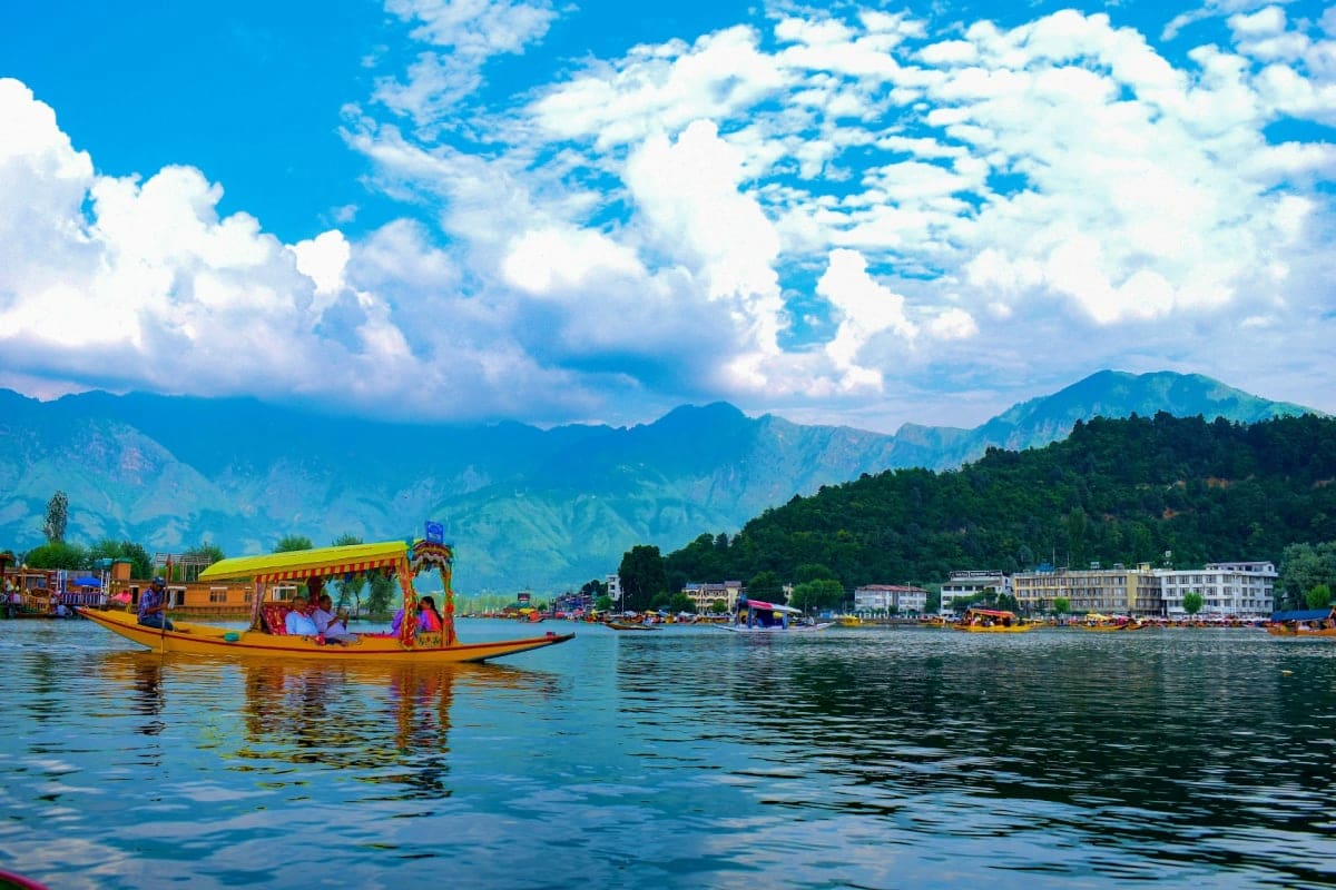 Colorful traditional wooden houseboat on Dal Lake in Srinagar with snow-capped Himalayan mountains and blue sky in background