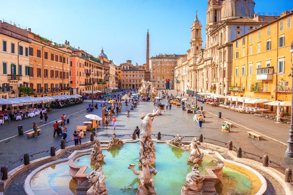 Piazza Navona in Rome with Fountain of Neptune, colorful Renaissance buildings, tourists, and outdoor cafes under blue sky