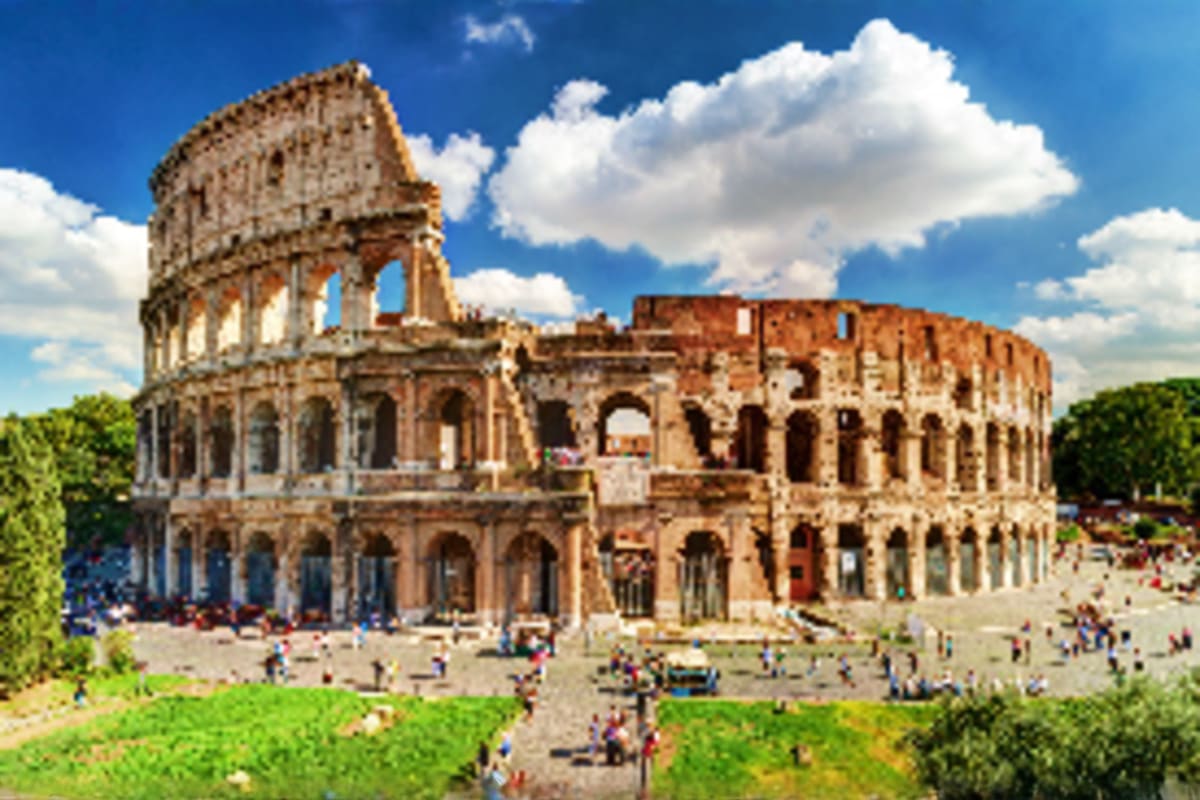 The Colosseum in Rome with tourists in the plaza on a sunny day with blue sky and white clouds