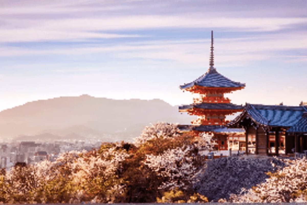 Traditional red Japanese pagoda with blue tile roof overlooking snowy landscape and distant city in mountain valley