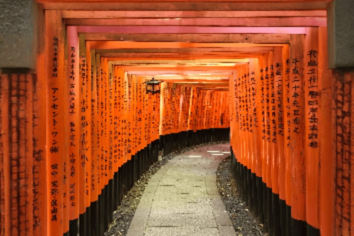 Thousands of bright orange torii gates creating a tunnel pathway at Fushimi Inari Shrine in Kyoto, Japan