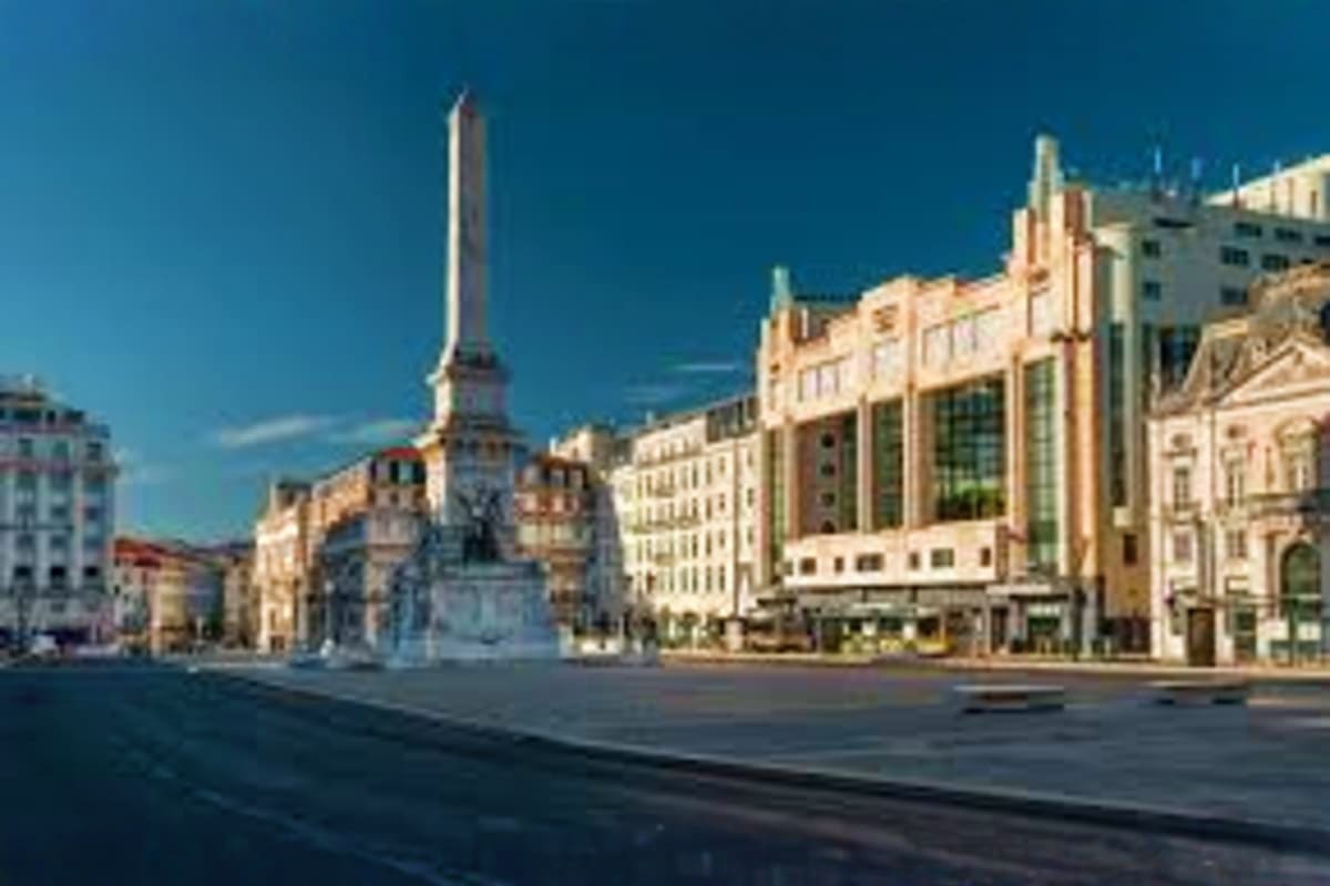 Southern Spain with Lisbon Tour Historic plaza in Lisbon featuring a tall monument surrounded by classical European architecture and clear blue sky