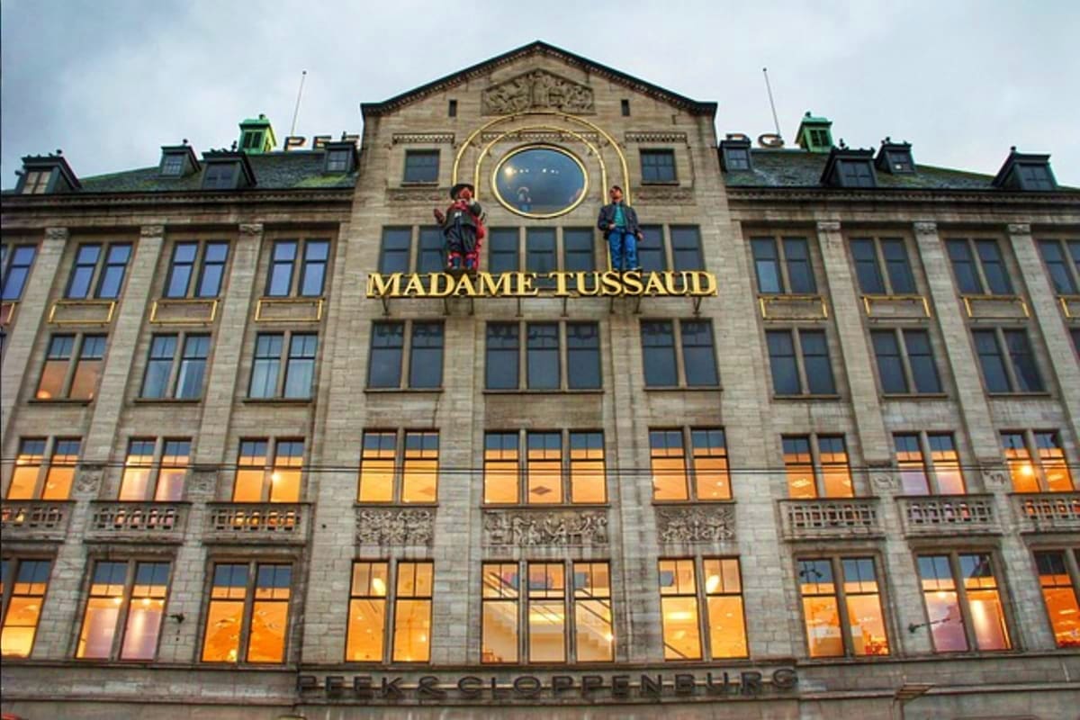Madame Tussauds wax museum building facade in Amsterdam with illuminated windows and clock tower at dusk