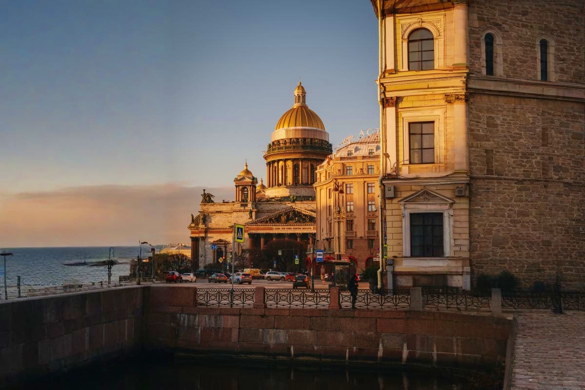 Saint Isaac's Cathedral with golden dome at sunset reflected in canal water, St. Petersburg Russia