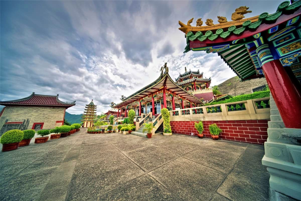 Explore Manila And Cebu at Your Own Pace Traditional Chinese temple courtyard with ornate red and green roofs, golden dragon decorations, pagoda tower, and manicured