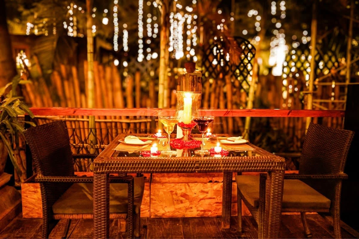 Eternal Romance in Georgia Romantic outdoor dinner table set for two with candlelight, wine glasses, and decorative string lights overhead at night