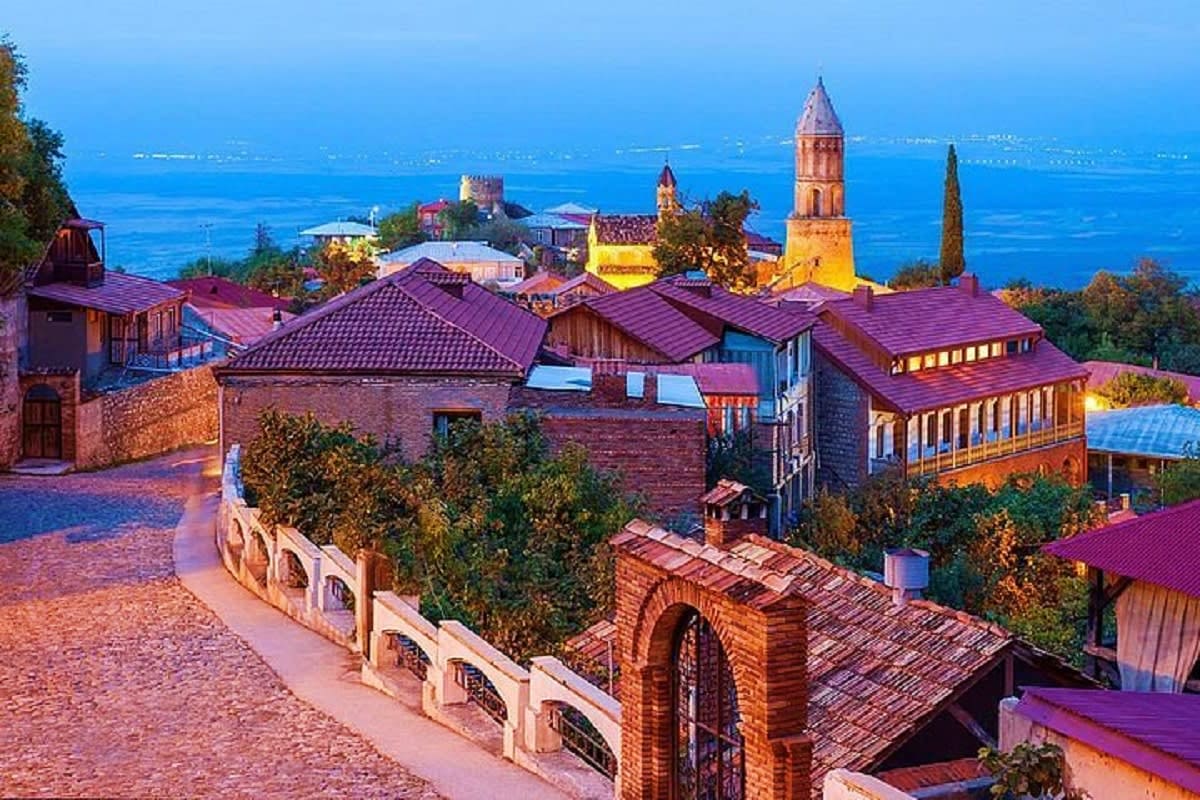 Twilight view of Metekhi Church and historic fortress overlooking the Black Sea coast in Batumi, Georgia, with illuminated bu