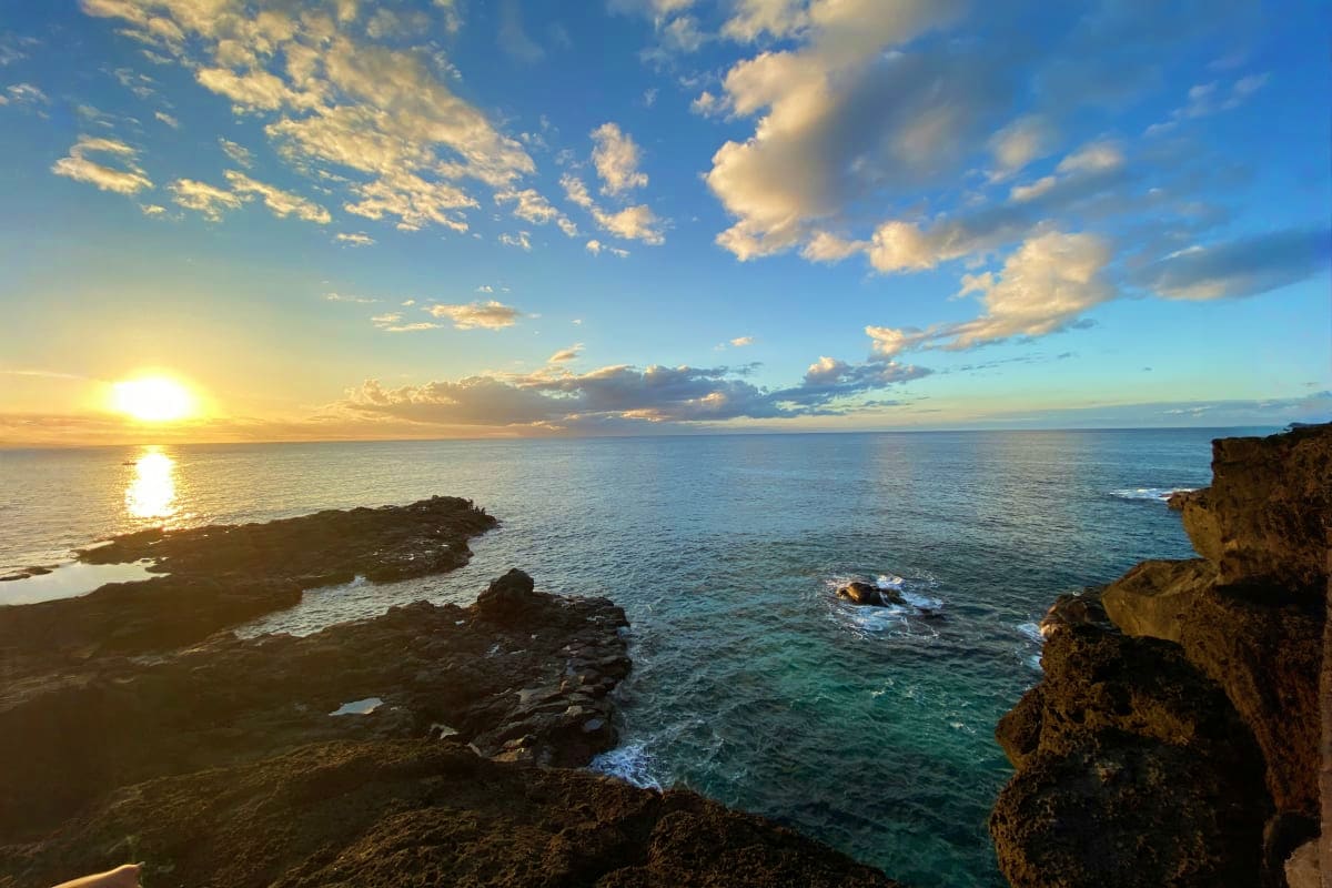 Mauritius Royal Escape Sunset over rocky coastal cliffs and turquoise ocean waters in Mauritius with golden sunlight reflecting on the sea