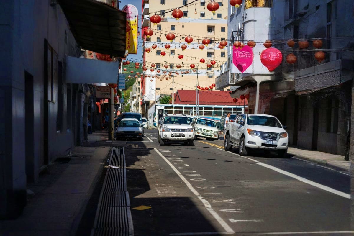 San Francisco Chinatown street with red lantern decorations and parked white vehicles along urban buildings