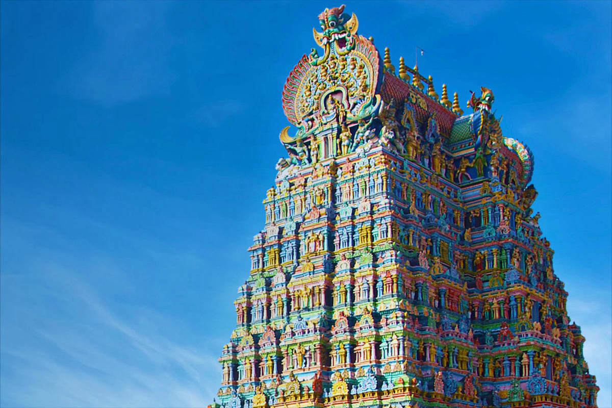 Best Rameshwaram Kanyakumari Tour from Madurai Colorful ornate Hindu temple tower with intricate carved details and golden spires against blue sky in South India