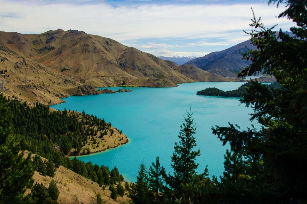 Turquoise alpine lake surrounded by barren mountains and coniferous forests in Armenia's highlands