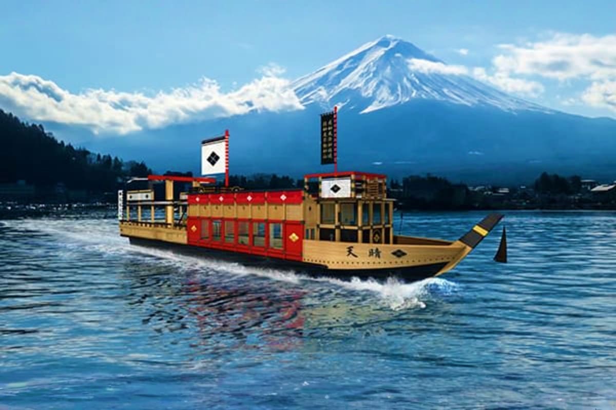 Traditional Japanese wooden boat with red and gold trim on Lake Yamanaka, snow-capped Mount Fuji in background