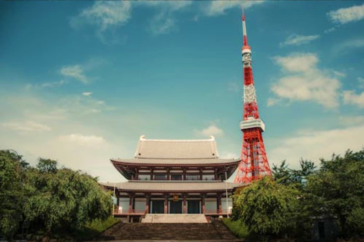 Tokyo Tower and traditional Japanese temple with curved roofs against blue sky
