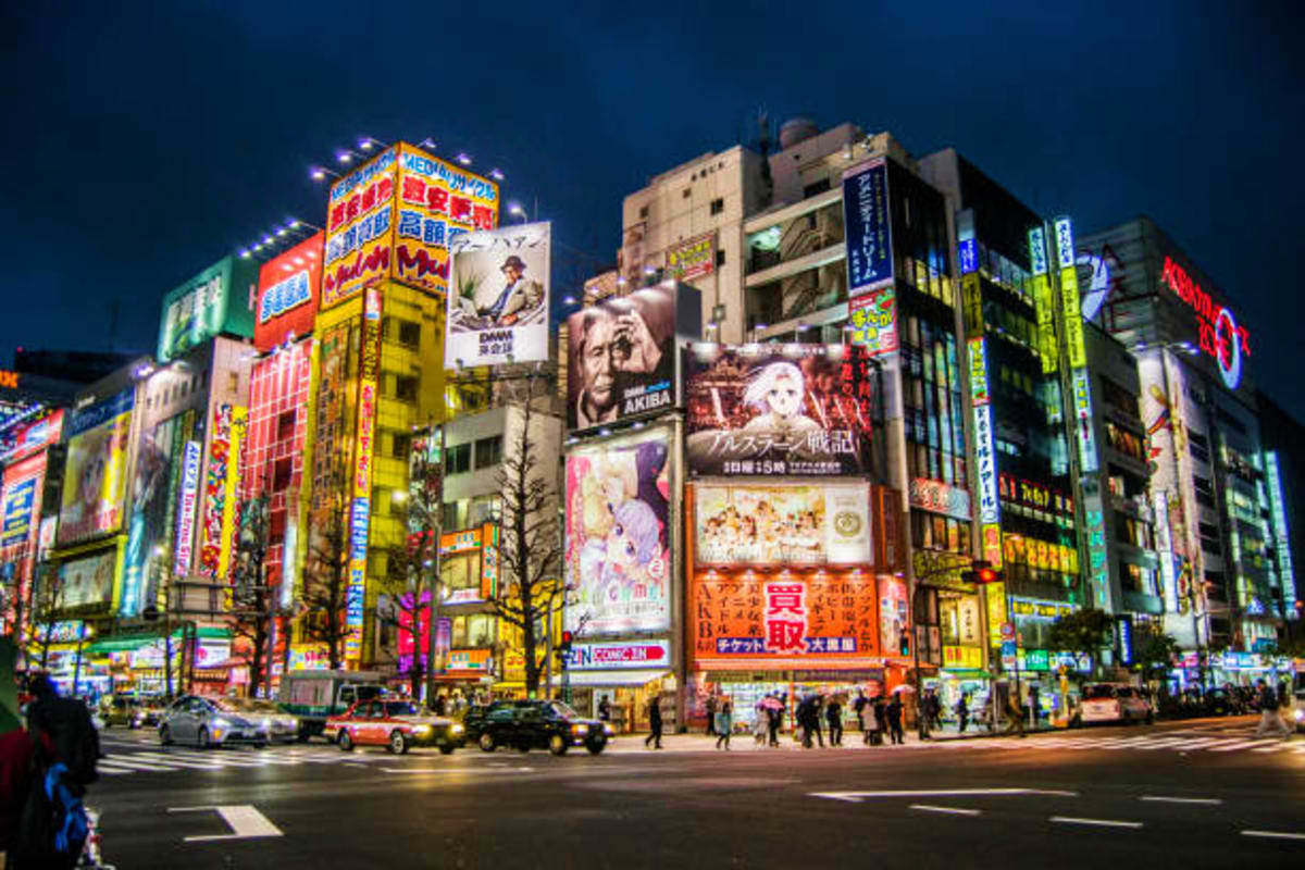 Shibuya Crossing at night illuminated with colorful neon signs and digital billboards on surrounding buildings