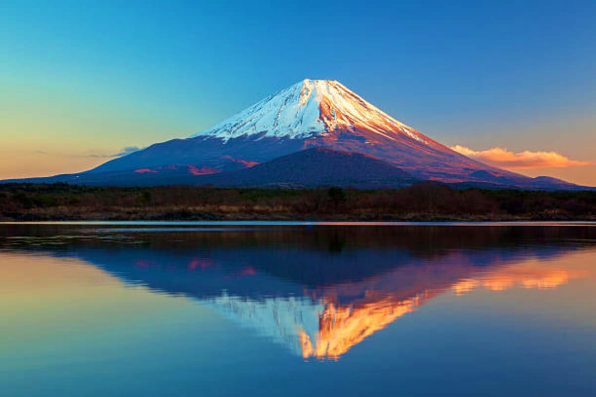 Mount Fuji snow-capped peak reflected in still lake water at sunset, central Japan landscape