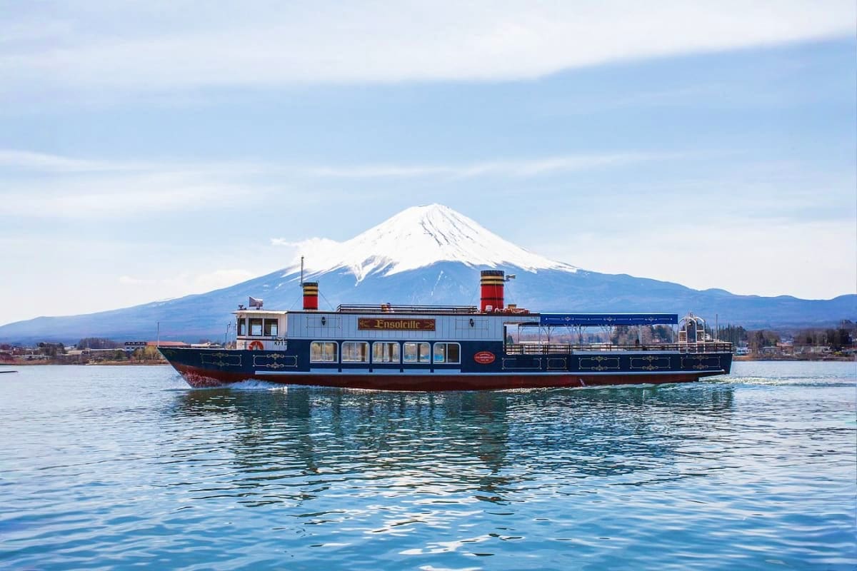 Tourist sightseeing boat on Lake Yamanaka with snow-capped Mount Fuji in the background under clear blue sky