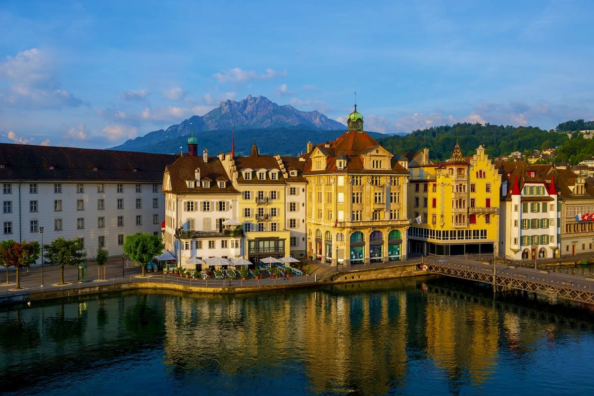 Lucerne Old Town waterfront with colorful historic buildings, chapel bridge, and Mount Pilatus in the background, Switzerland