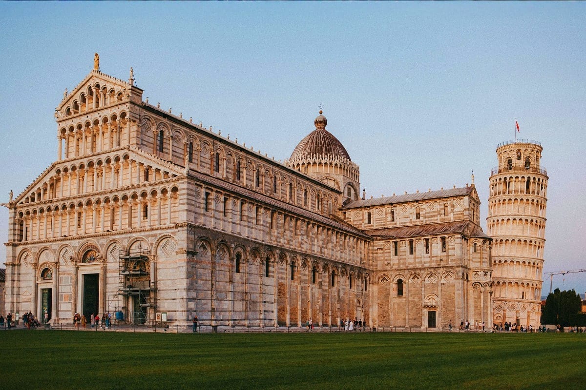 Pisa Cathedral and Leaning Tower of Pisa in Italy, historic Romanesque architecture with marble facade and green lawn in fore
