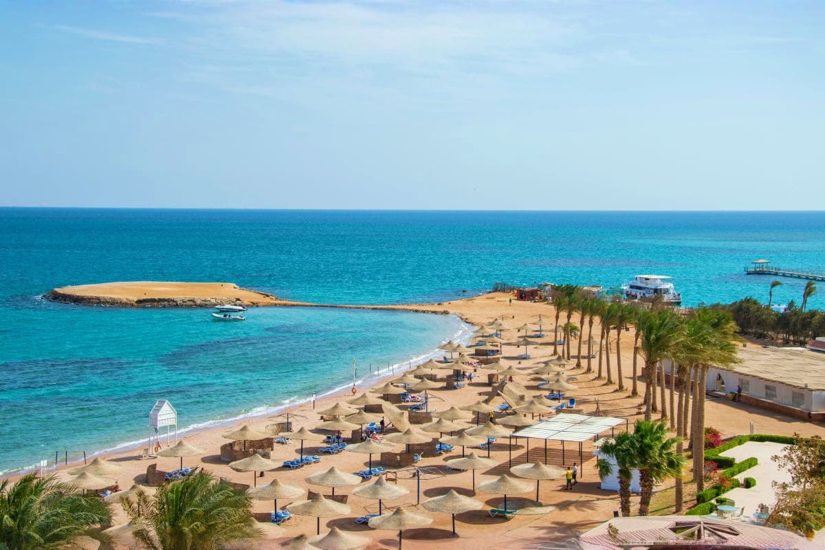 Panoramic view of Hurghada beach resort in Egypt with turquoise waters, sandy shore, palm trees, and beach umbrellas along th
