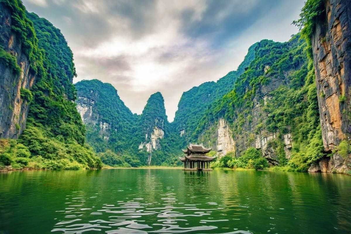 Halong Waves and Phu Quoc Days Traditional pagoda temple on emerald water surrounded by towering limestone cliffs in Halong Bay, Vietnam