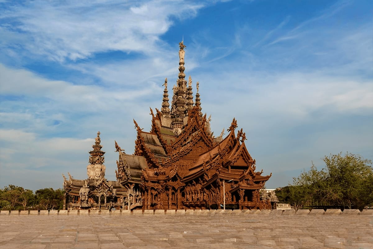 Ornate golden Thai temple with intricate spires and traditional architecture set in open courtyard under blue sky