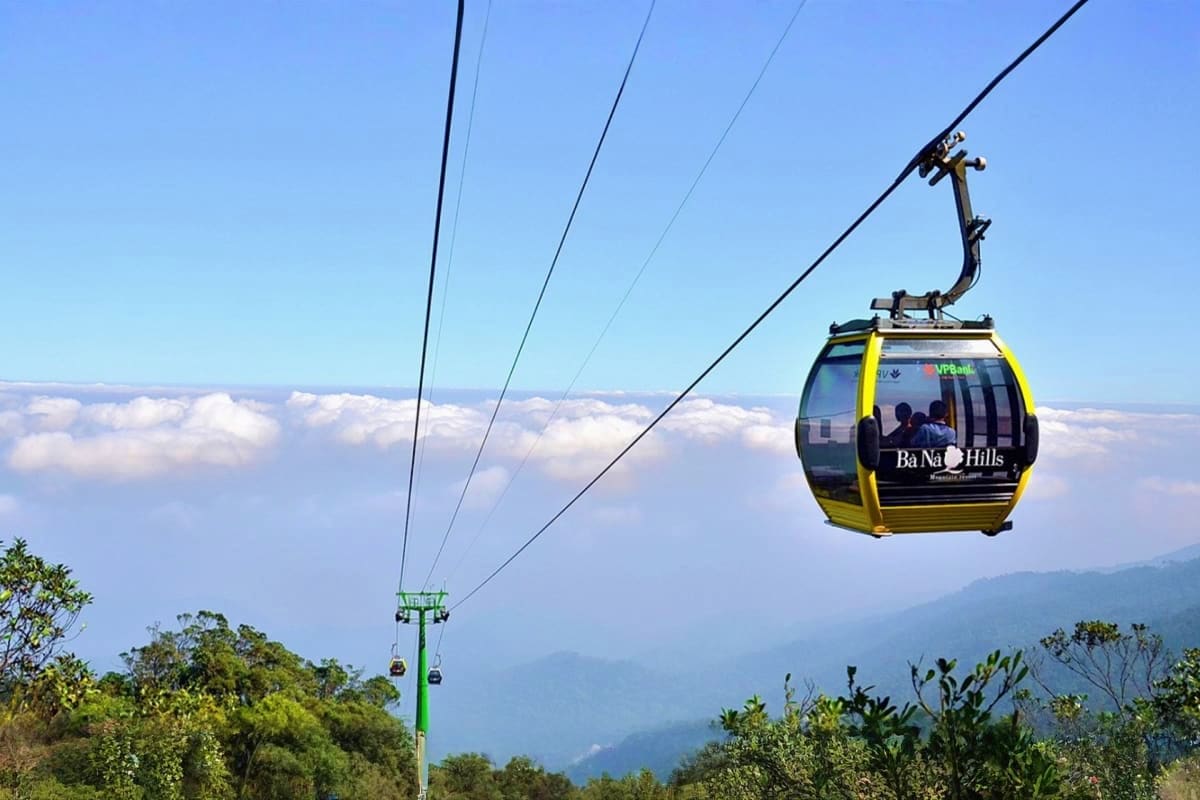 Ba Na Hills cable car ascending above misty clouds and forested mountains in central Vietnam