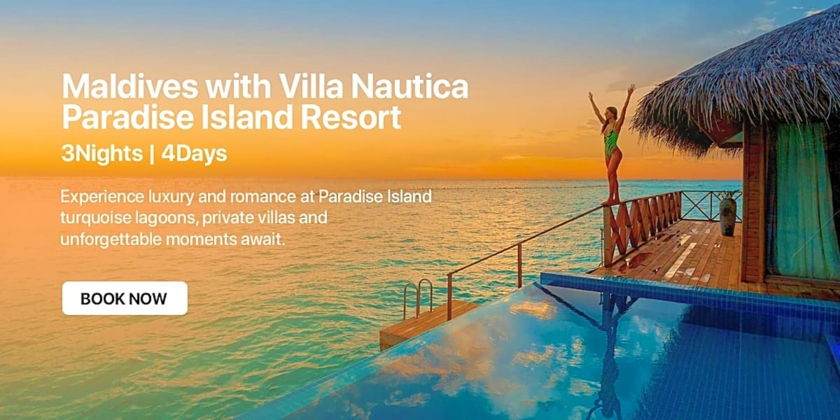 Woman with arms raised on wooden deck of overwater villa at sunset in Maldives with turquoise lagoon and thatched-roof bungal