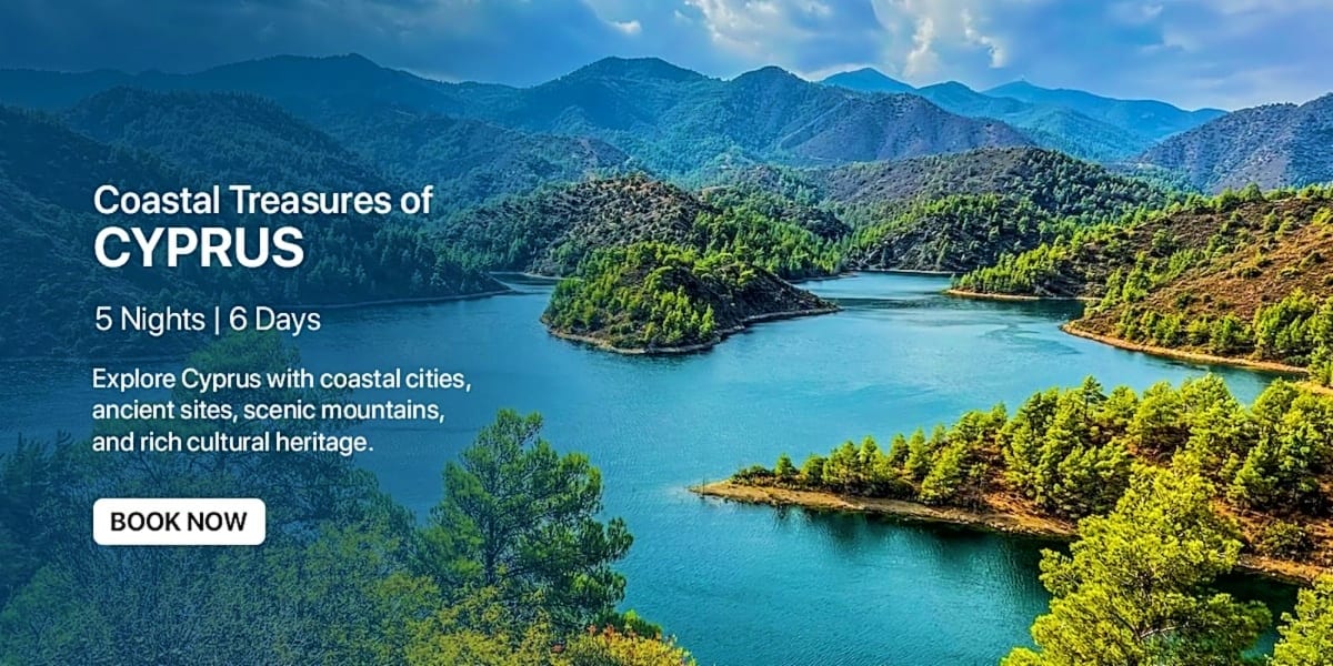 Aerial view of turquoise lake surrounded by forested mountains and rocky coastline in Cyprus