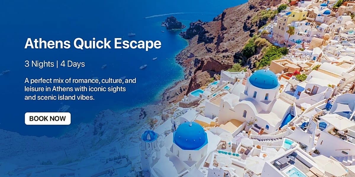 Aerial view of Santorini's whitewashed buildings with blue-domed churches overlooking turquoise Mediterranean waters and rock