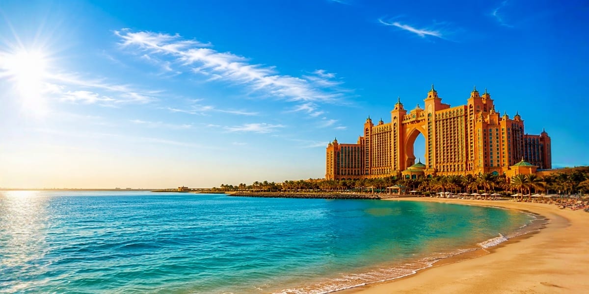Atlantis The Palm resort hotel with golden architecture overlooking turquoise beach and Arabian Gulf waters under blue sky in