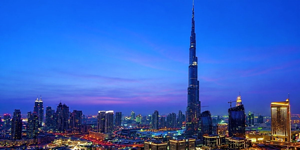 Dubai skyline at dusk with Burj Khalifa illuminated against purple and blue twilight sky surrounded by glowing skyscrapers
